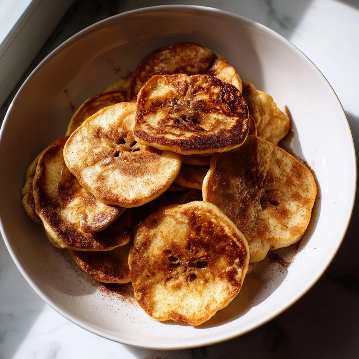 Warm, bubbling Baked Apple Slices coated in cinnamon, ready with melted butter for a sweet treat.