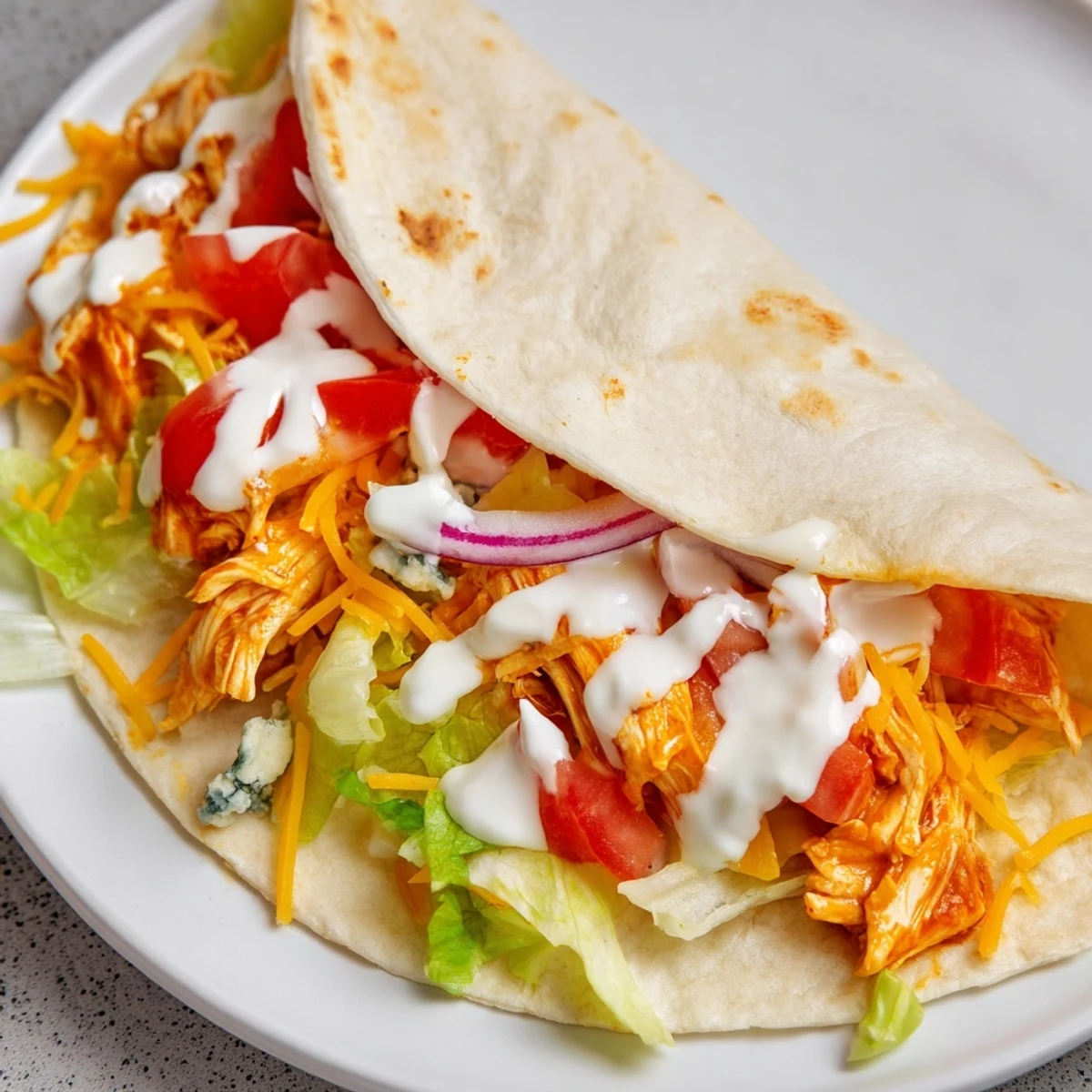 Golden-brown folded Buffalo Chicken Wrap, showcasing a cross-section of colorful fillings and crispy edges.