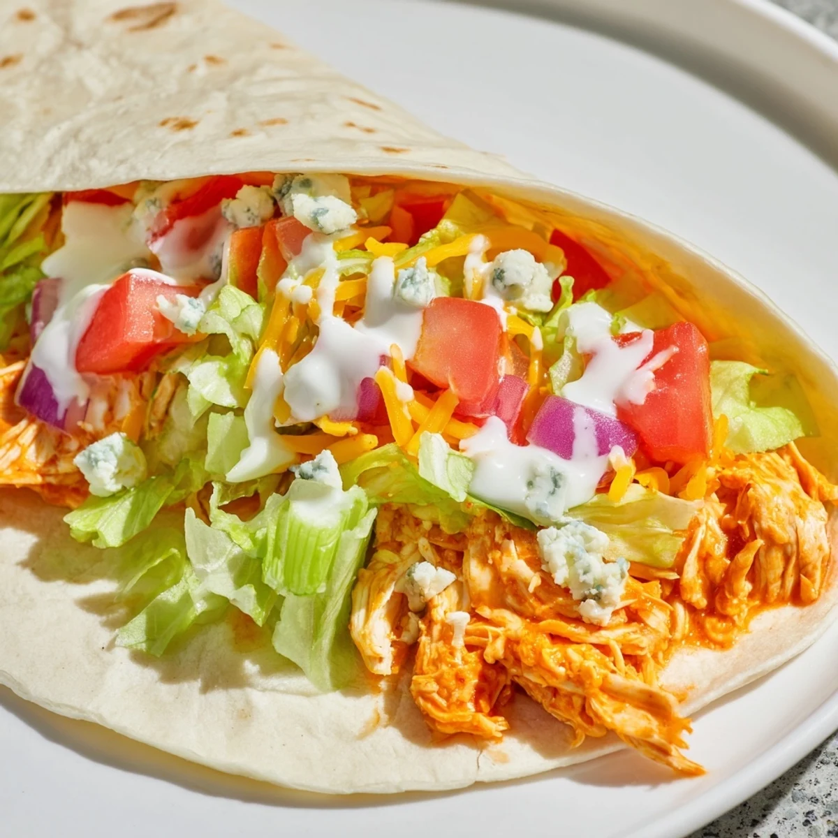 Close-up of a generously filled Buffalo Chicken Wrap, showcasing the juicy chicken and vibrant vegetables.