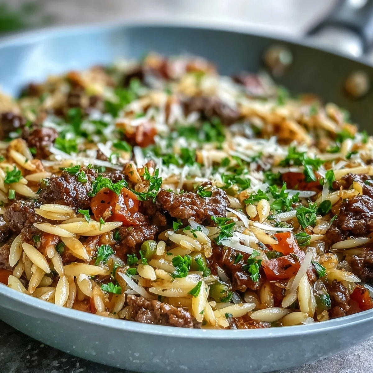 Savory Comforting Ground Beef Orzo Dinner simmers with sweet bell peppers, tomatoes, and orzo, offering a rich, bubbling, one-skillet meal suggestion.