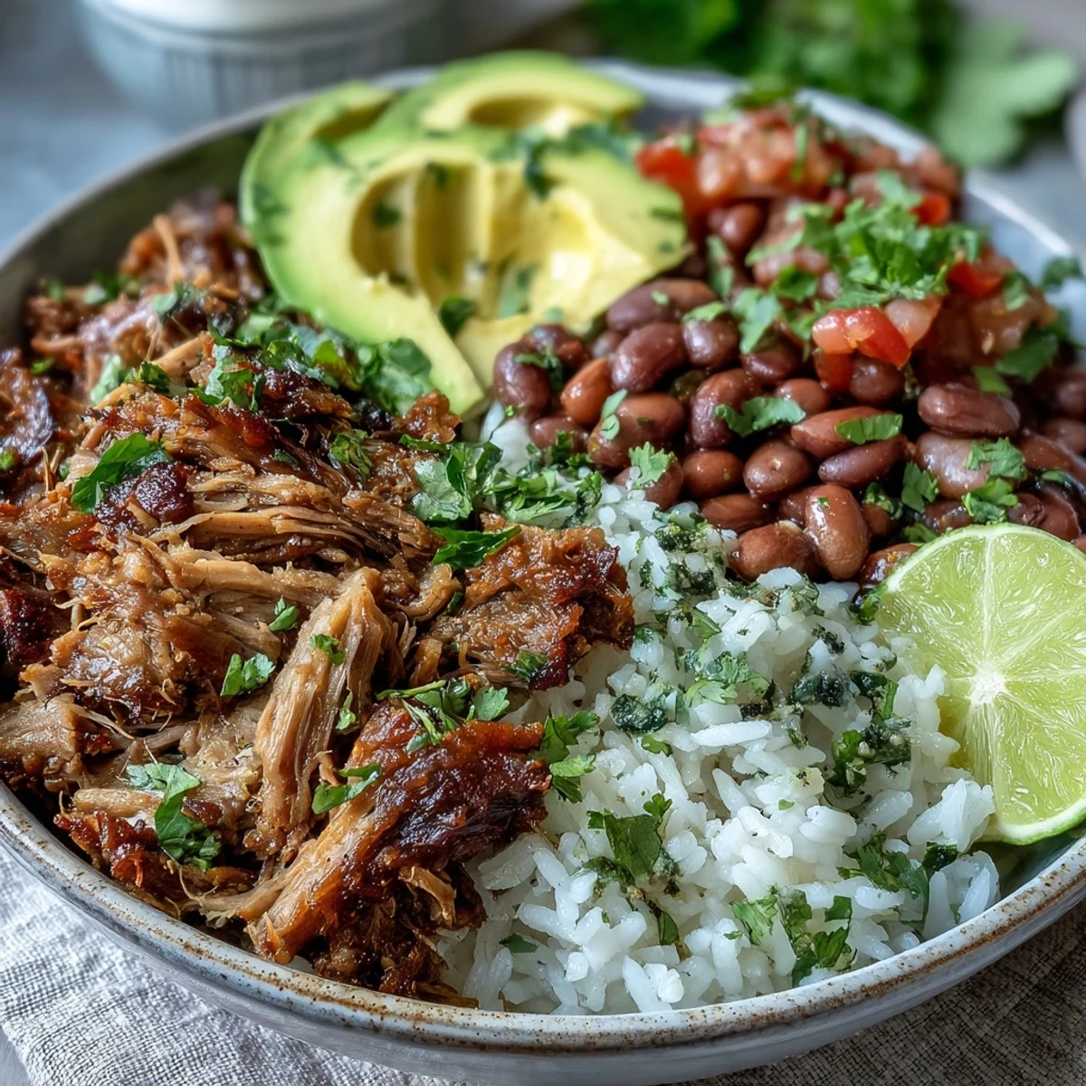 Golden-brown crispy carnitas with fluffy rice, pinto beans, fresh avocado, and pico de gallo in a rustic ceramic bowl.