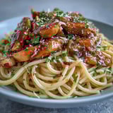 Hot Sticky Honey Garlic Chicken Pasta topped with sliced chicken, parsley, and red pepper flakes, ready to serve for a quick weeknight dinner.