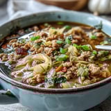 Cozy One-Pot Egg Roll Soup with Green Onions and Ginger served steaming hot in a rustic ceramic bowl, ready for a comforting meal.