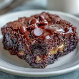 A close-up of Rich Peanut Butter Cup Dump Cake served warm, with a scoop of vanilla ice cream melting into the rich dessert.