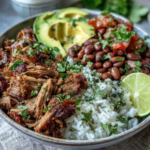 Golden-brown crispy carnitas with fluffy rice, pinto beans, fresh avocado, and pico de gallo in a rustic ceramic bowl.
