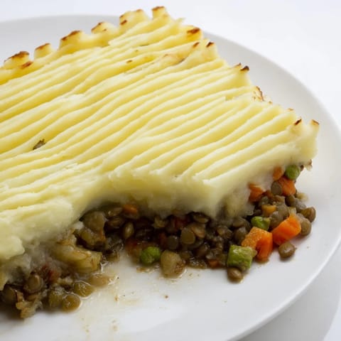 A close-up of a steaming bowl of vegan Hearty Lentil Shepherd's Pie, showcasing the hearty filling.