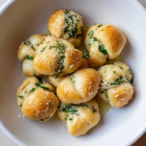 Warm, golden Homemade Garlic Knots glistening with garlic butter, perfect for dipping in marinara sauce.