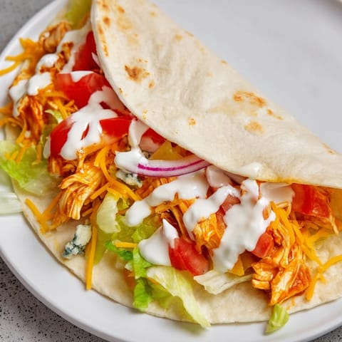 Golden-brown folded Buffalo Chicken Wrap, showcasing a cross-section of colorful fillings and crispy edges.