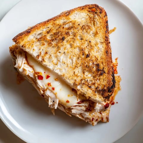 This satisfying Chili Crisp Honey Chicken Grilled Cheese shows a crispy, buttery sandwich, ready to enjoy.