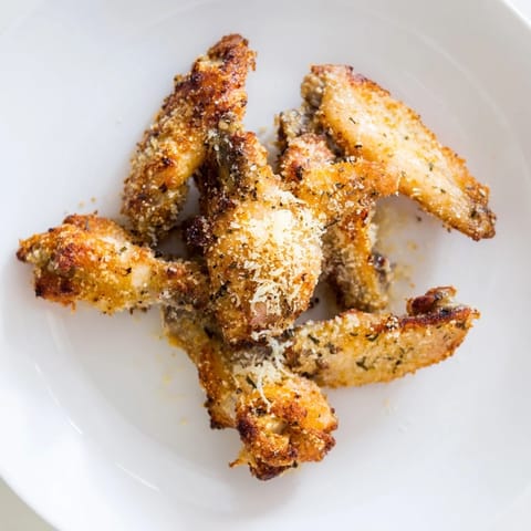 A close-up of delicious, savory Parmesan-covered Baked Chicken Wings, perfect for game day.