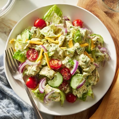 A vibrant bowl of Jalapeño Ranch Chicken Salad with diced chicken, fresh veggies, and a zesty, herb-flecked dressing.
