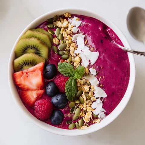 The thick Beet and Berry Smoothie Bowl features creamy crimson base and crunchy pumpkin seeds.