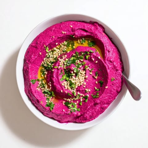 Smooth Roasted Beet Hummus served alongside crunchy pita chips and sliced cucumbers for a colorful, fresh appetizer spread.