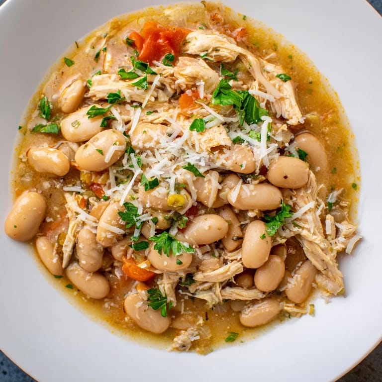 Flavorful white bean and roasted red pepper chicken, garnished with fresh parsley and Parmesan, ready to enjoy with crusty bread.
