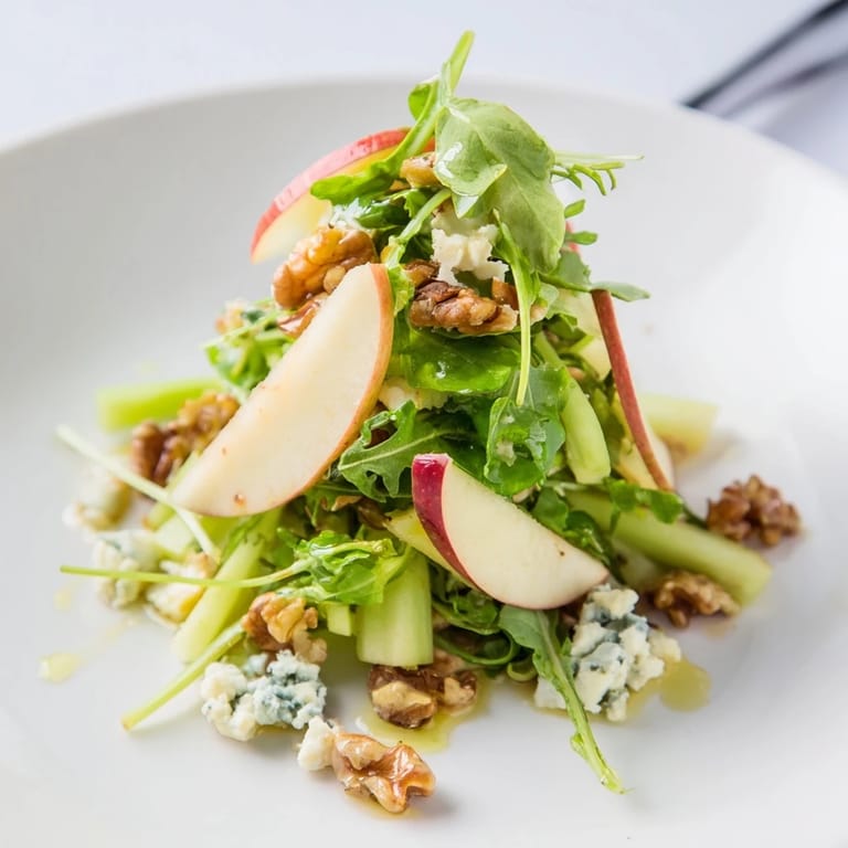 A vibrant bowl of Apple and Walnut Salad featuring crisp celery, feta crumbles, and a drizzle of zesty apple cider dressing.  