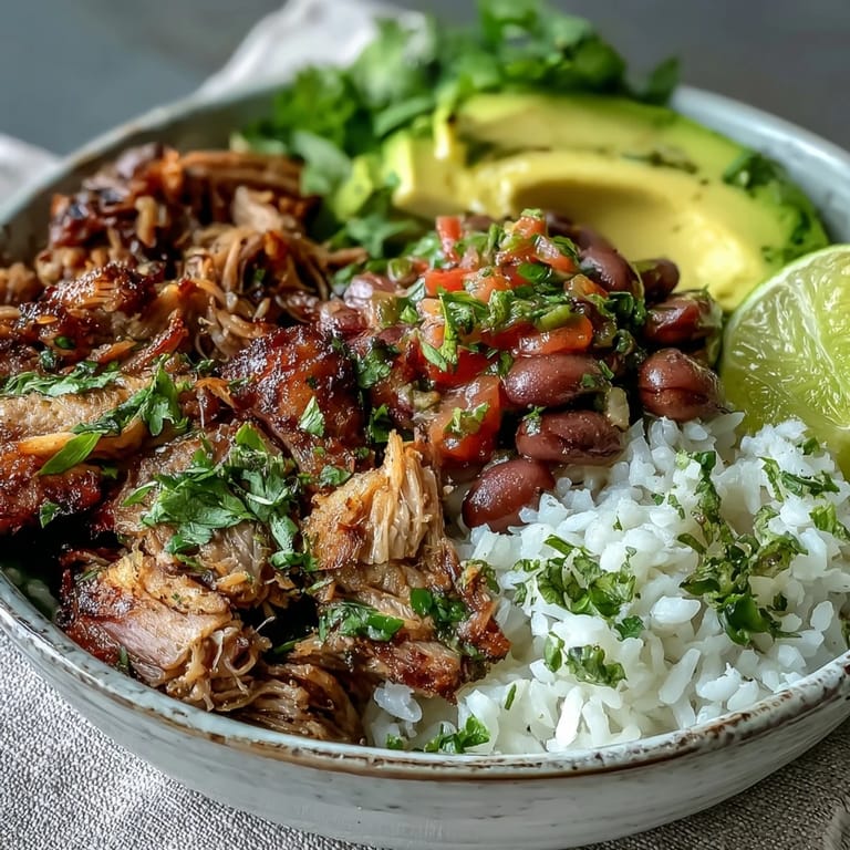 A hearty Mexican carnitas bowl garnished with cilantro and lime wedges, served on a wooden table for a family meal.
