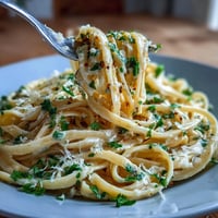 Lemon Butter Pasta with Peas and Parmesan in a creamy, citrusy sauce, topped with grated cheese and fresh parsley.